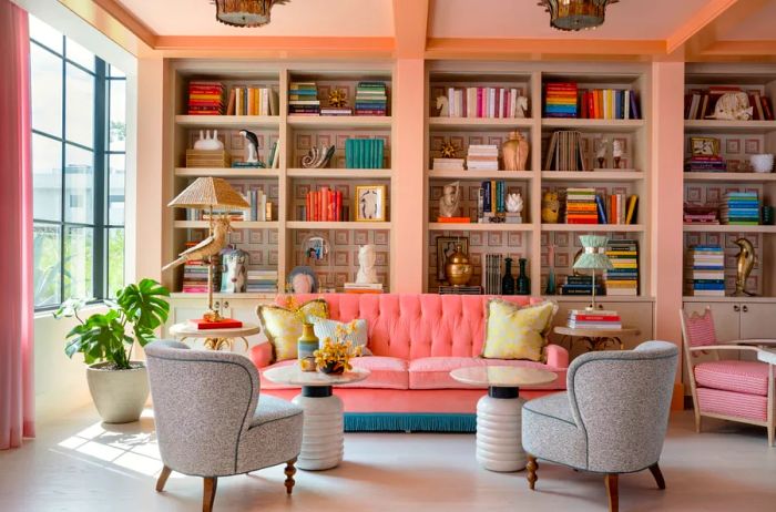 The Library at the Goodtime Hotel features a pink tufted couch and a beautifully arranged wall of bookshelves.