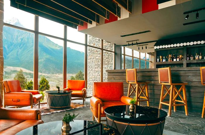 The Aara Bar at Shinta Mani Mustang is vibrant, with bright orange chairs and expansive floor-to-ceiling windows that provide breathtaking views of the surrounding mountains.