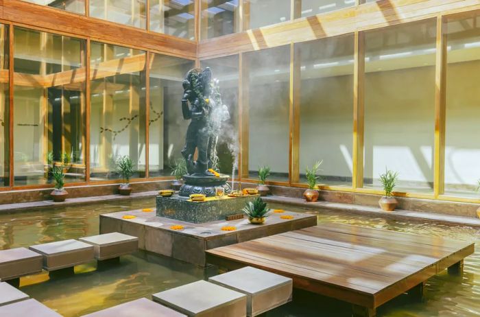 An interior courtyard at the Ayurveda Center in Six Senses Vana features a shallow pool, small plants, and a decorative statue.