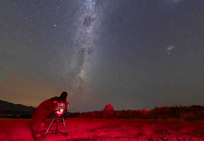 An individual gazing through a telescope during the Dark Sky Project's Crater Experience in Takapō at night