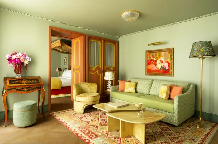 A suite at Le Grand Mazarin, featuring soft green furnishings, intricately carved doors, and fresh floral arrangements.