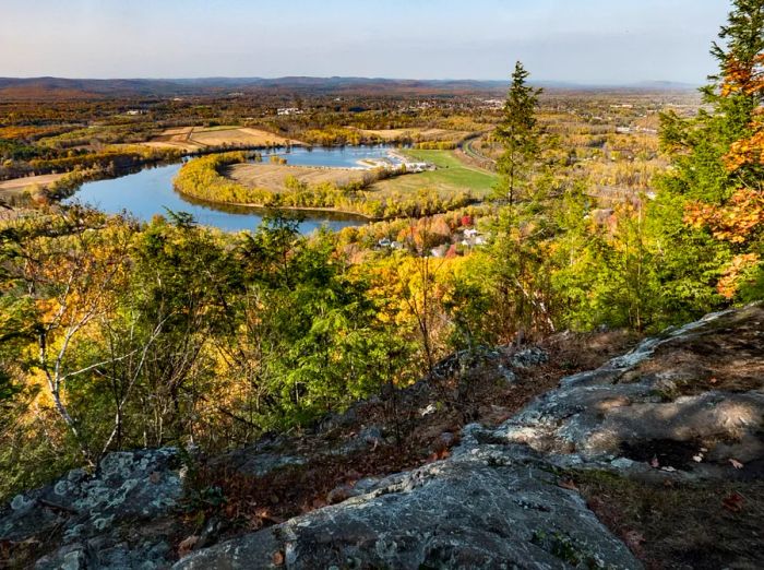 An oxbow lake viewed from a hillside, with rocks and trees in the foreground.