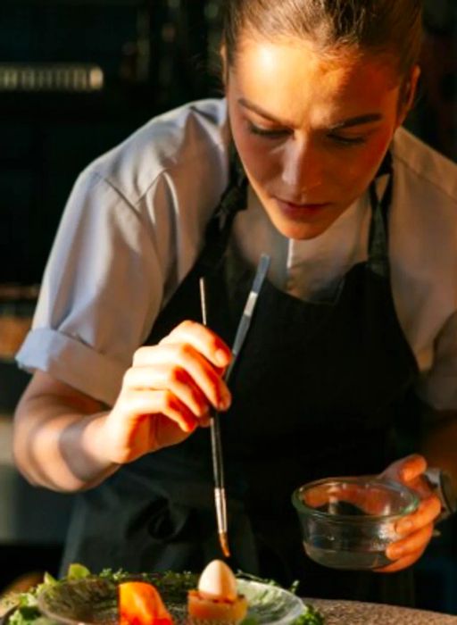 A chef at Credo applies the final touches to a dish using a paintbrush.