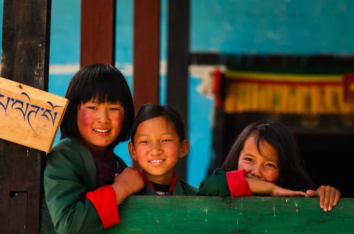 Three children beaming at a village school in Bhutan.