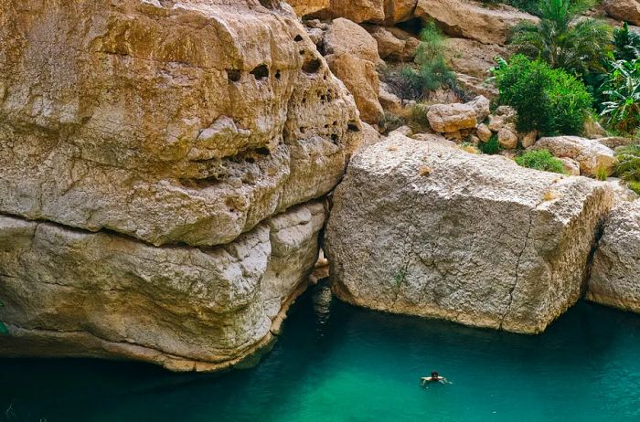 An aerial perspective of a person swimming in Wadi Shab.