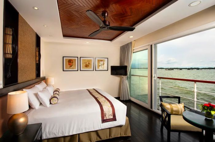 A stateroom aboard the 'Avalon Saigon' river cruise ship features a large bed that faces an open French balcony.