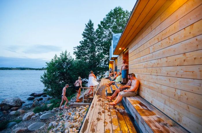 Individuals in swimsuits enjoying the outdoors at the Lonna public sauna in Helsinki