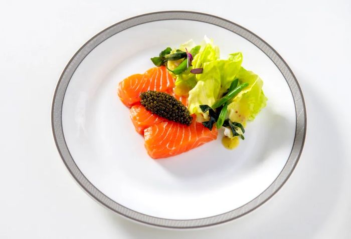 A dish featuring smoked trout, caviar, lettuce, beans, wakame, and a tarragon mustard dressing, served on Singapore Airlines.