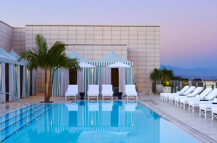 Rooftop pool at the Waldorf Astoria Beverly Hills, featuring green-striped cabanas