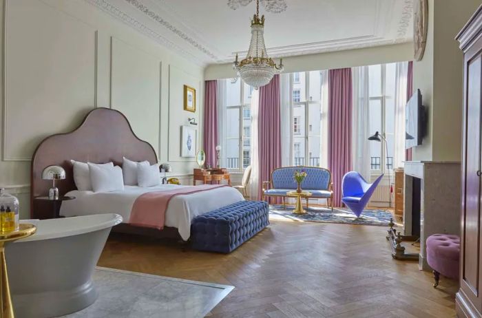 The luxurious Pulitzer Suite at the Hotel in Amsterdam features plush, antique-style furnishings, soaring ceilings, and an elegant chandelier above the bed.