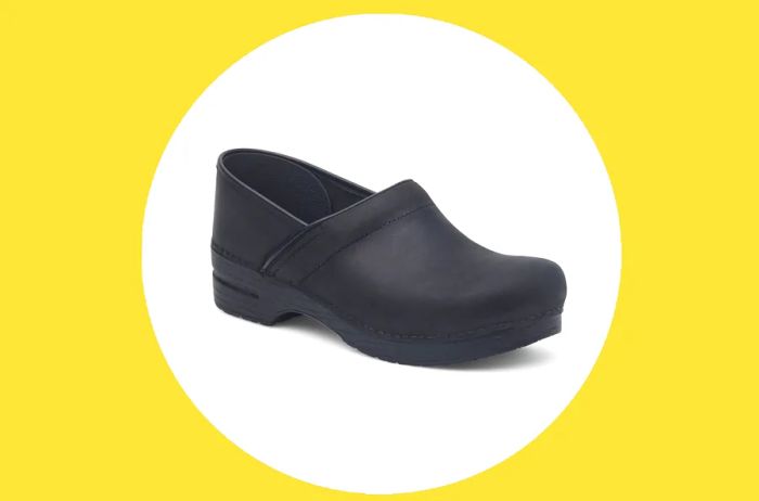 A single black Dansko professional clog displayed on a white circle against a yellow background