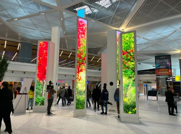 Visitors stroll past towering digital art columns in Newark's Terminal A.