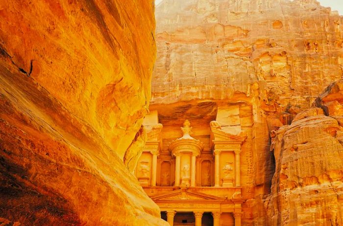 A stunning view of Petra in Jordan, a UNESCO World Heritage Site, showcasing a cathedral meticulously carved from the vibrant red rock formations.