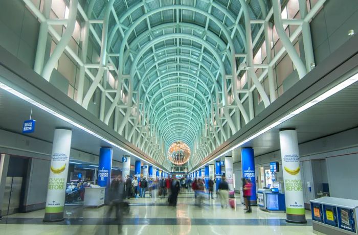 A long concourse featuring a high arched ceiling with a few travelers moving about at Chicago O'Hare International Airport.