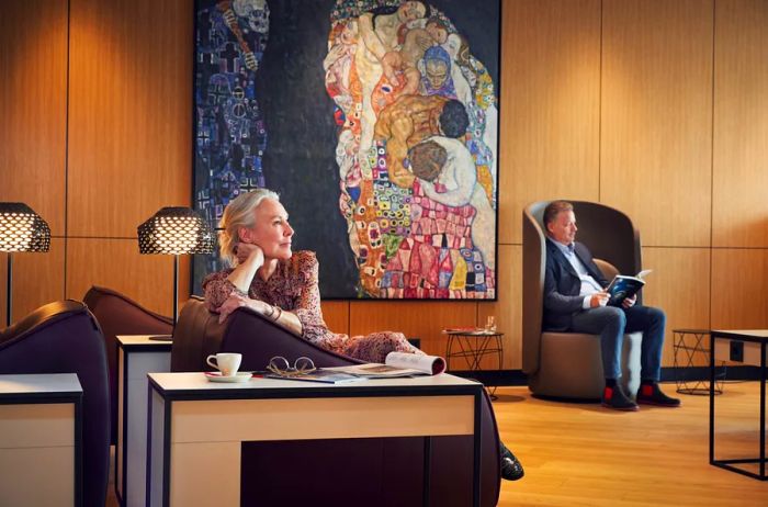 A woman relaxes in front of a painting by Gustave Klimt at the Vienna Lounge located in Vienna Airport.