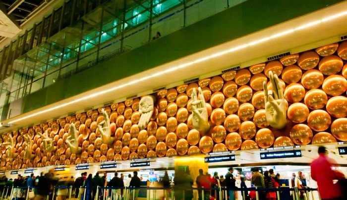 The arrivals area at Indira Gandhi International Airport features impressive large sculptures depicting mudra hand gestures above the travelers.