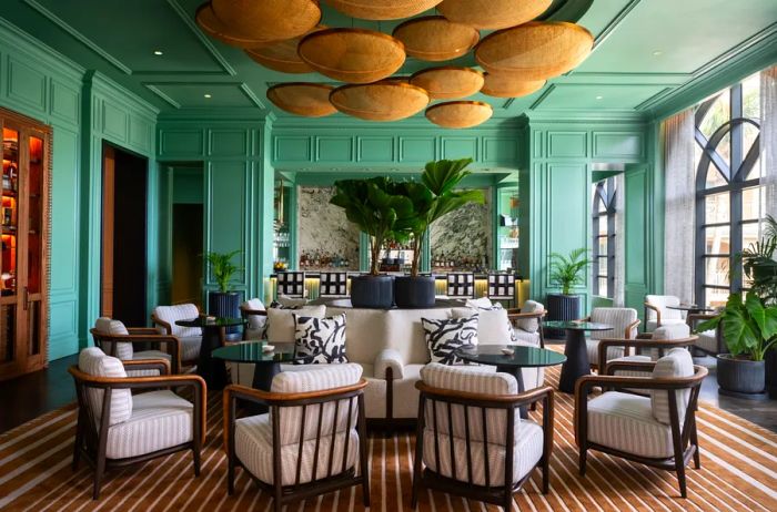 The Silver Palm bar and lounge at the Ritz-Carlton Grand Cayman features tropical plants, comfortable seating, and a unique basket-shaped lighting fixture overhead.