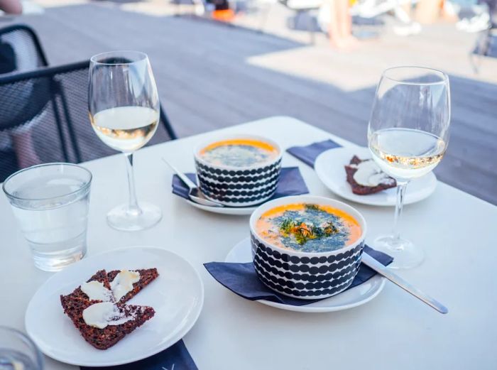 Two bowls of salmon soup elegantly presented on a white tablecloth at Löyly, a sauna restaurant by the Baltic Sea