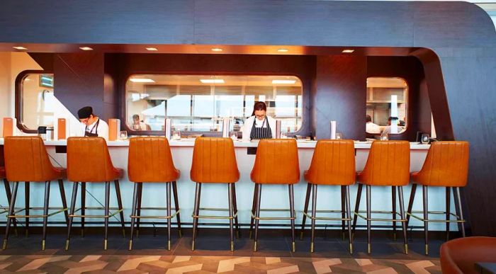 A row of empty brown stools at the bar in Gordon Ramsay Plane Food, located in Heathrow's Terminal 5.