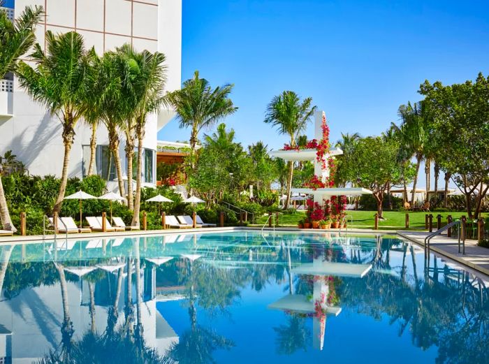 The pool at the Miami Beach EDITION is encircled by palm trees.