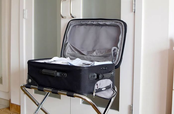 A luggage rack featuring a black suitcase opened and placed on top of it