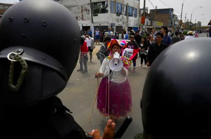 An antigovernment protester confronts police at San Marcos University in Lima, Peru.<br/>