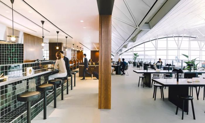 Guests enjoying drinks at the bar and seated at various tables in Cathay Pacific's spacious and bright business-class lounge, known as the Deck, in Hong Kong.