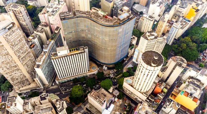 Aerial view showcasing the skyline of São Paulo, featuring the iconic wavy Copan building and a circular white tower.