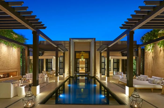 A serene pool terrace at the Mandarin Oriental Marrakech, featuring daybeds and traditional lanterns.