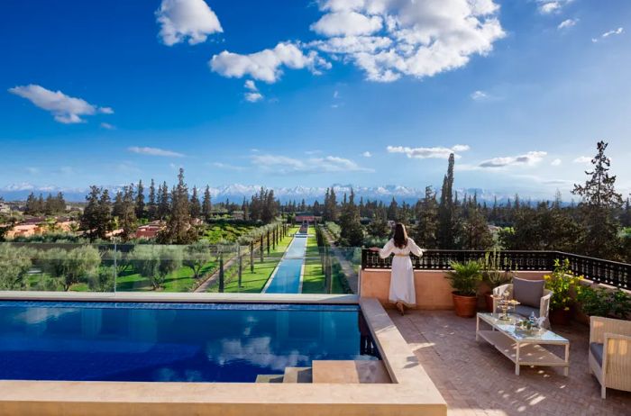 The pool area at Oberoi Marrakech offers stunning views over the expansive, tree-filled estate.