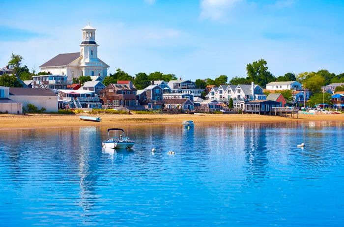 Tranquil waters and the shore of Provincetown beach, with quaint white buildings in the background