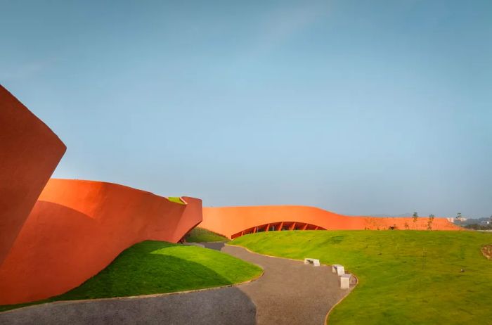 A low, curving building in terra-cotta tones winds gracefully along the landscape.