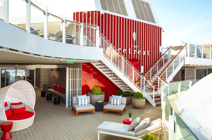 The Retreat features a striking red and white exterior, showcasing a private resort area onboard the ship, complete with numerous vacant chairs.