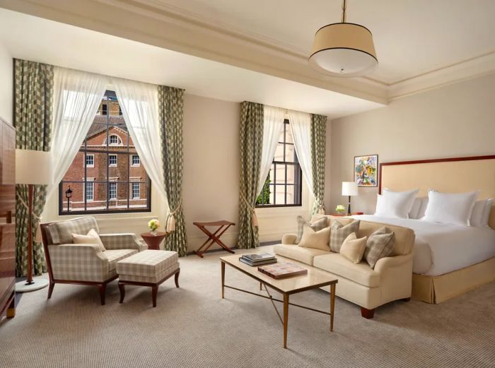 A junior suite at Raffles London at the OWO, showcasing modern furnishings and a neutral color palette.