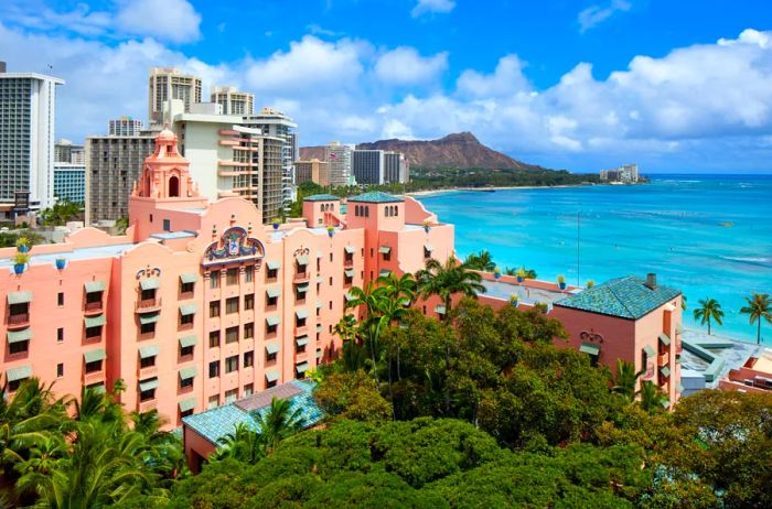 Aerial view showcasing the exterior of the iconic pink Royal Hawaiian, with Diamond Head in the background.