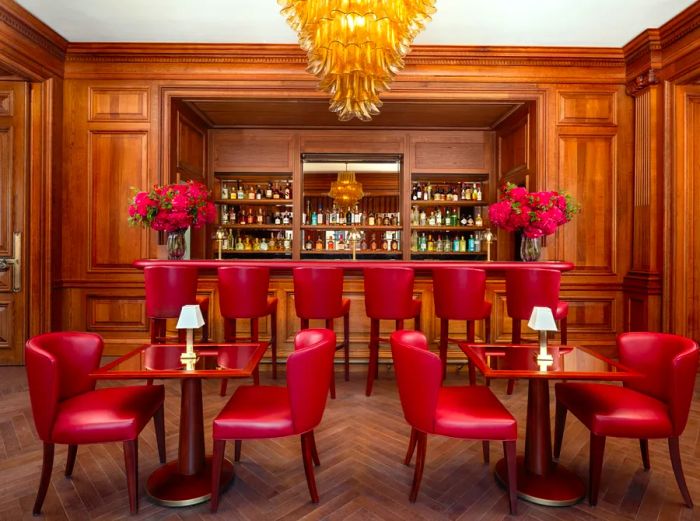 The Guards Bar boasts wood-paneled walls, plush crimson chairs, and an elegant chandelier.