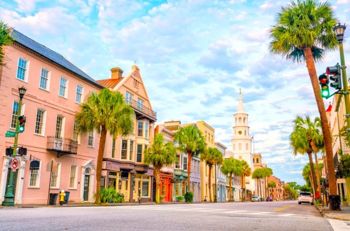 Pastel-colored houses line a quiet street, with a white church at the end.