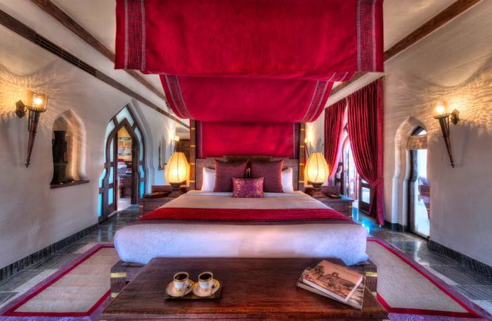 This room at Evolve Back Kamalapura Palace features a large bed and windows adorned with rich red drapes.