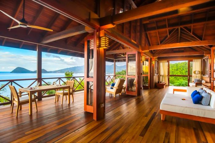 A suite's living room at Secret Bay, showcasing wooden flooring and a high ceiling that opens to an outdoor deck.