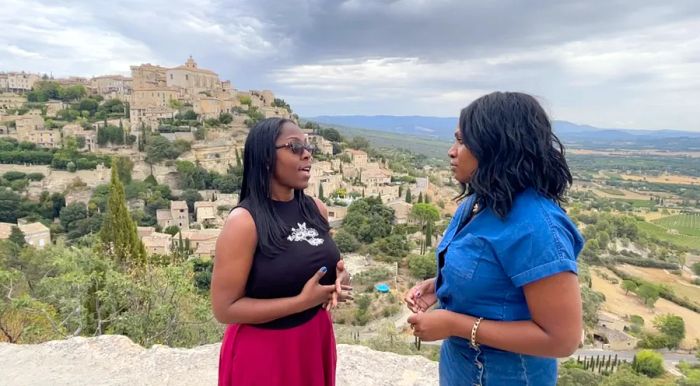 Jackie Williams, owner of NuVibe Travel Experiences, converses with the author on a cliff with a view of Gordes, Provence.