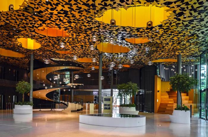 A breathtaking spiral staircase adorned with hanging globe lights and an ornate ceiling at the House of Music Hungary.