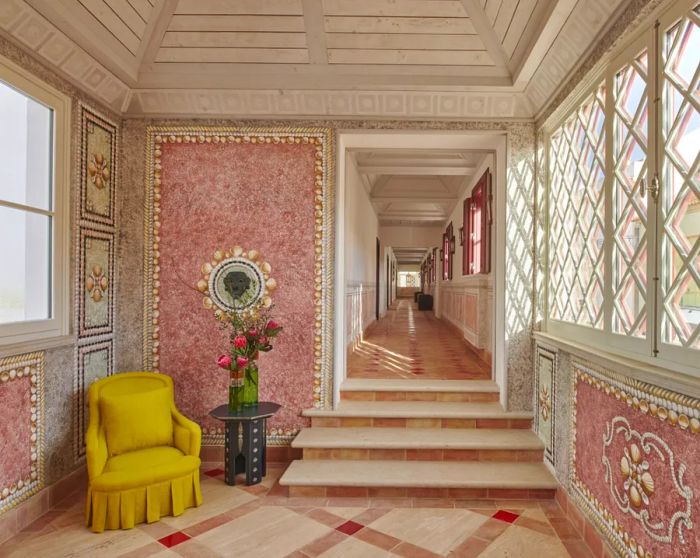 This corridor in the Vermelho Hotel features vibrant pink walls paired with a mustard yellow chair.