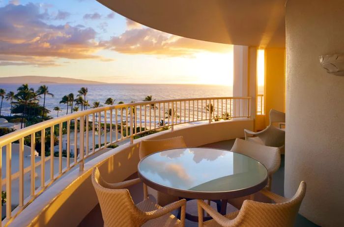 A beautifully curved lanai featuring a round table and four chairs, all with a stunning view of the Pacific Ocean.