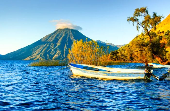 The stunning view of San Pedro Volcano across Lake Atitlán, with a small rowboat in the foreground.