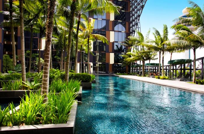 A spacious outdoor swimming pool at the Crowne Plaza Changi Airport in Singapore, surrounded by lush palm trees.