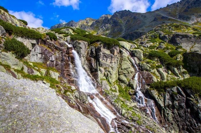 A waterfall tumbling down rocky cliffs on a mountainside.