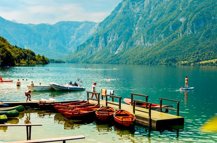 A canoe dock on Lake Bohinj, with several people enjoying the water.