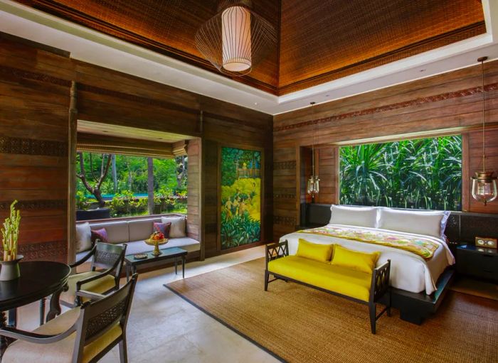 This guest room at Mandapa, a Ritz-Carlton Reserve, showcases wooden walls and a cozy window seat overlooking a vibrant garden.