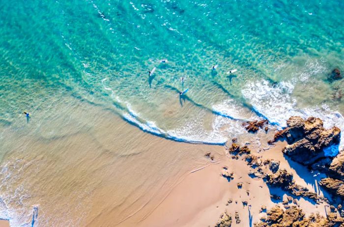 Bird's-eye view of surfers riding the waves near the shoreline