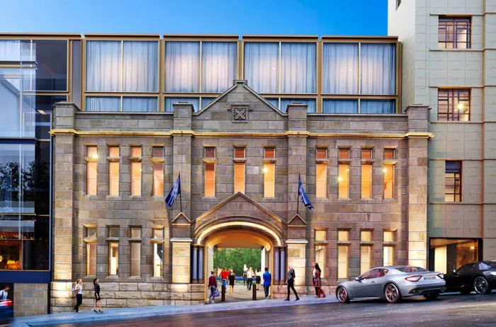 The historic gray stone facade features two rows of long, narrow windows in front of the hotel's modern section.